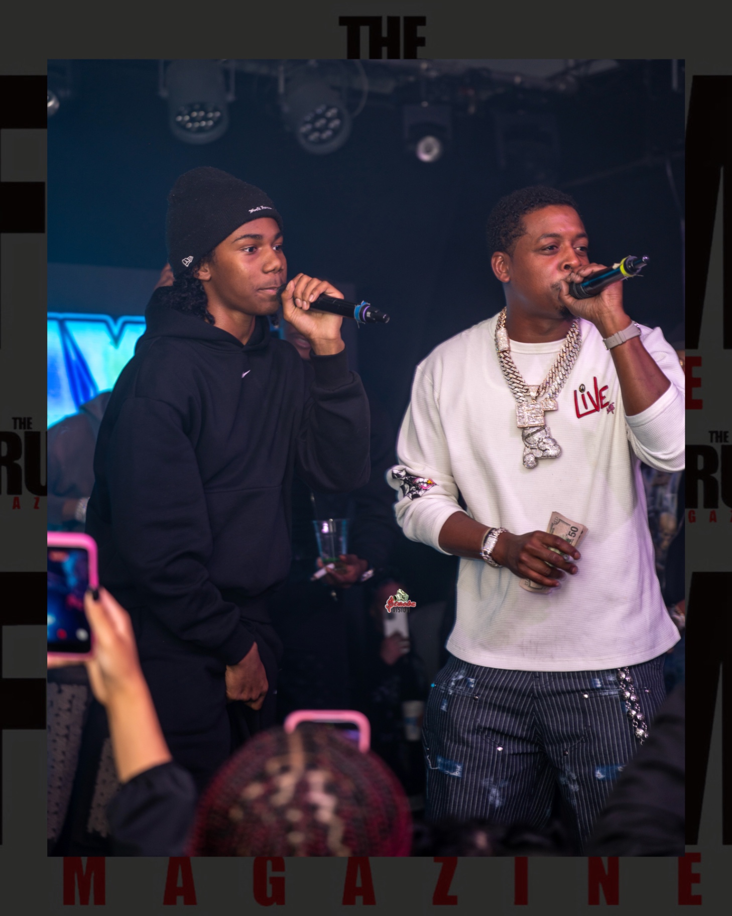 Baby Money on stage holding cash beside a young fan performing into a microphone