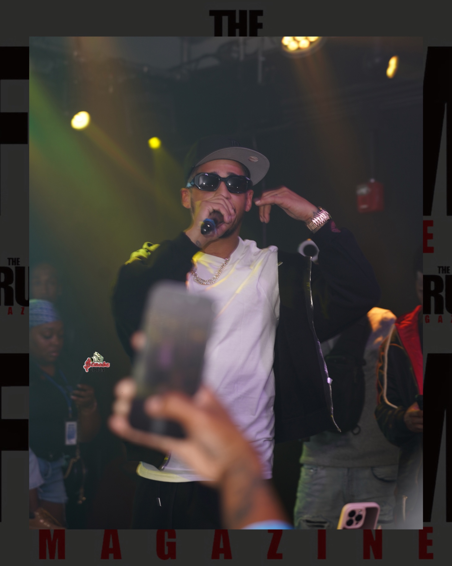 A performer on stage with a microphone as fans record from the crowd